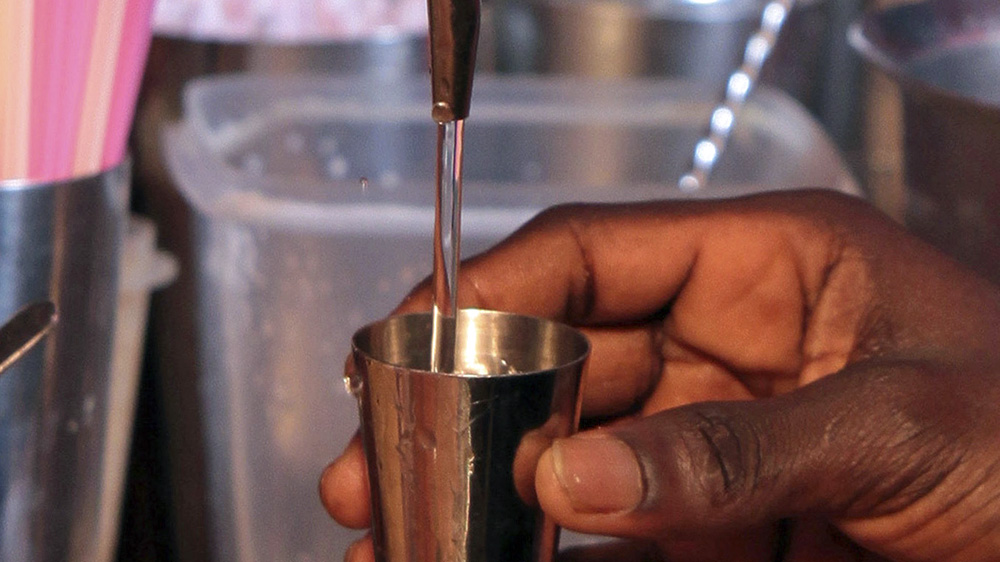 A bartender pours out a measure of local spirit akpeteshie as he prepares a cocktail at The Republic in Accra [AP]