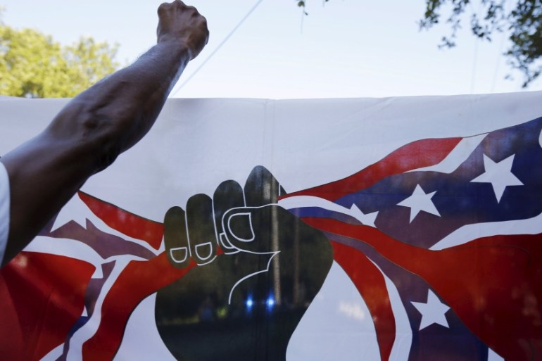 Demonstrators carry a flag showing a black fist closing around the confederate flag [REUTERS]
