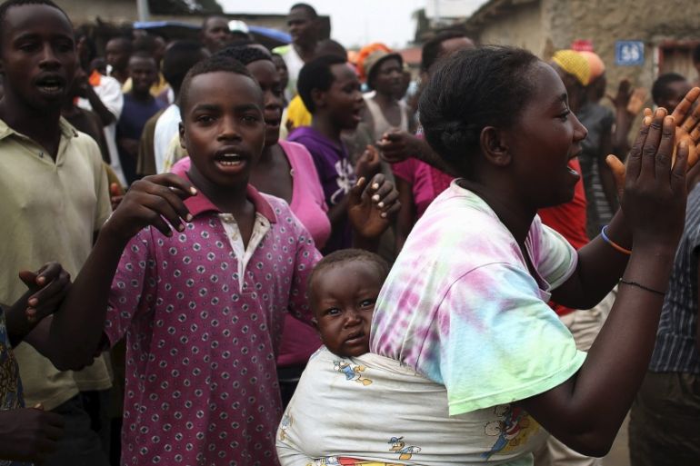 A protester dances as she carries her child in Bujumbura, Burundi [REUTERS]