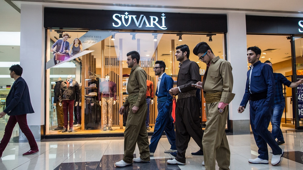 Young Kurdish men wearing traditional Kurdish clothes walk through a new shopping mall in Erbil [Mackenzie Knowles-Coursin]