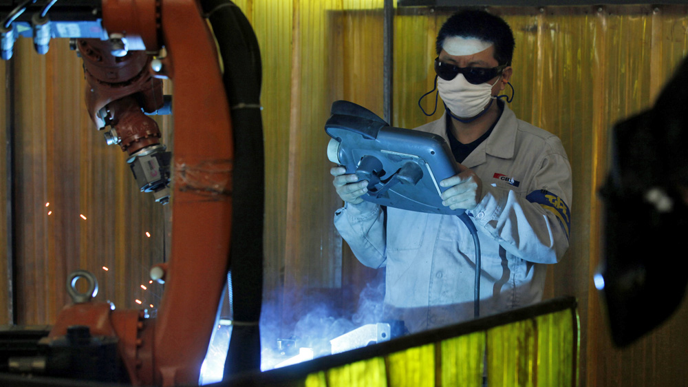 A worker uses welding robots to assemble brackets for hospital beds in Guangzhou, Guangdong province [AP] 
