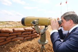 Turkish prime minister looks through binoculars at Syria from a Turkish military base at the border with Syria [Reuters]