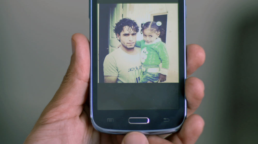 Mohamed Abdel-Muhsen holds up a picture of himself with his niece, taken two days before he lost his chin [Al Jazeera]