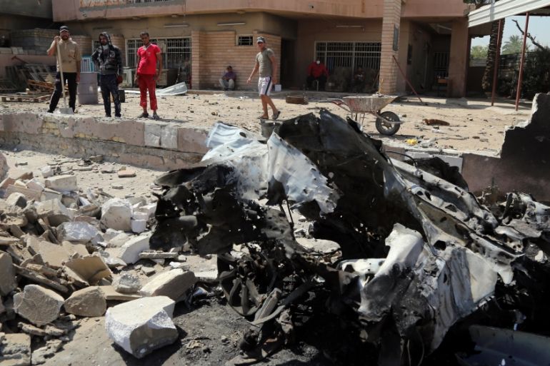 People inspect the scene of after an explosion hit a busy commercial area in Baghdad, Iraq