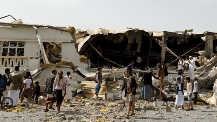 People gather outside a fabric factory after a Saudi-led air strike hit it in Sanaa