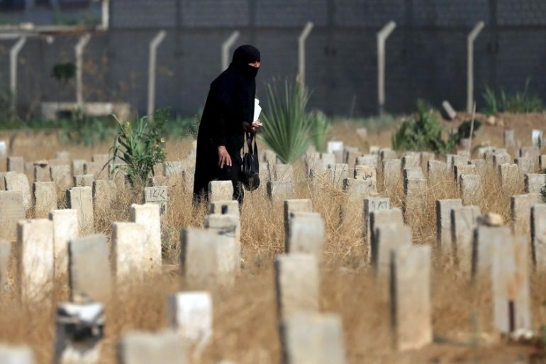 A woman walks past graves as she visits a cemetery