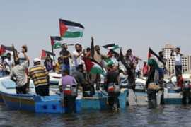 Palestinians riding boats hold Palestinian flags during a protest against the Israeli blocking of boat of foreign activists from reaching Gaza, at the Seaport of Gaza City