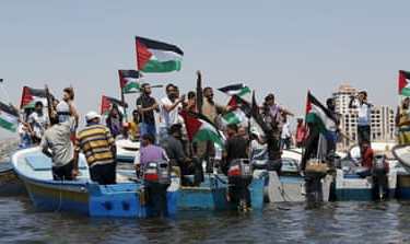 Palestinians riding boats hold Palestinian flags during a protest against the Israeli blocking of boat of foreign activists from reaching Gaza, at the Seaport of Gaza City
