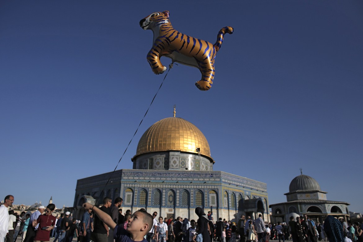 A Palestinian boy walks with a balloon in front of the Dome of Rock at the Al-Aqsa Mosque compound in Jerusalem''s Old City
