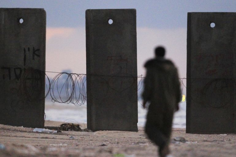 An Israeli fisherman walks near concrete barriers on Zikim beach, just outside the northern Gaza Strip