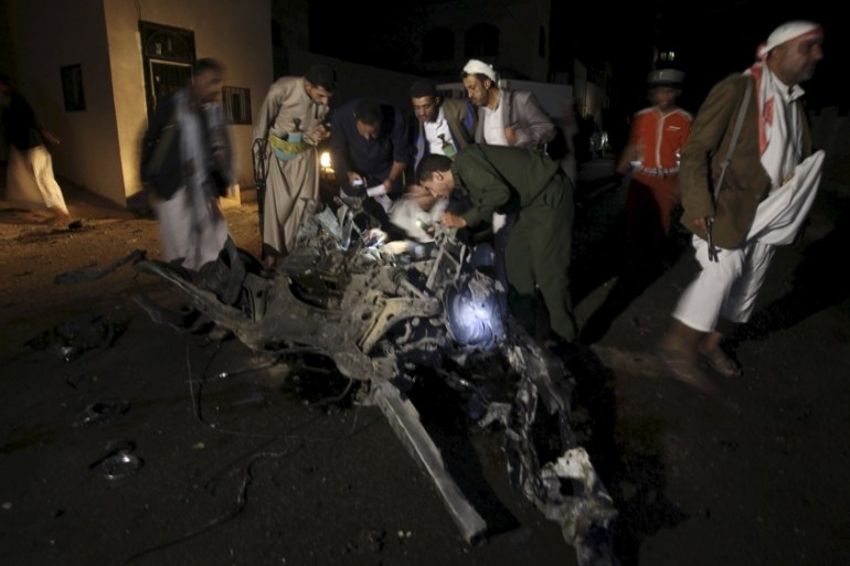 Police officers and Houthi militants inspect the site of a car bomb attack in Yemen''s capital Sanaa