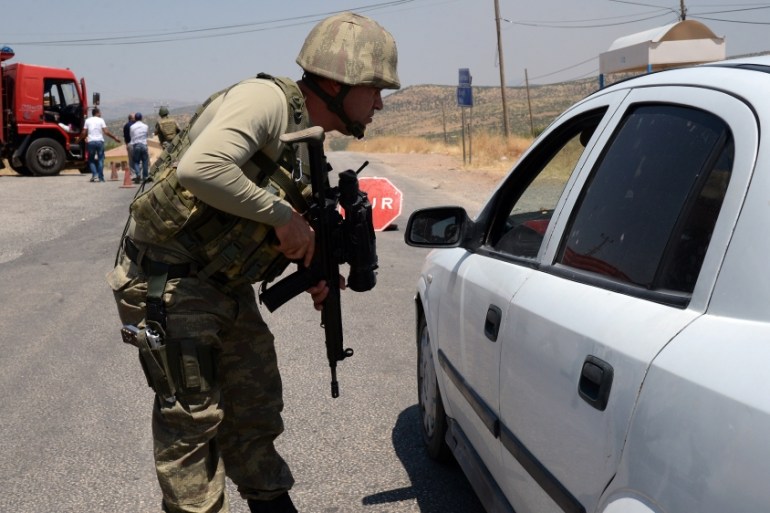 A Turkish soldier checks cars at a checkpoint in Diyarbakir on July 26, 2015 following the death of two