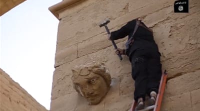 ISIL member destroying a face on a wall in Hatra [AP]