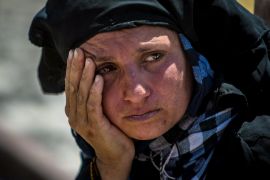 A woman rests after walking back to Tel Abyad town