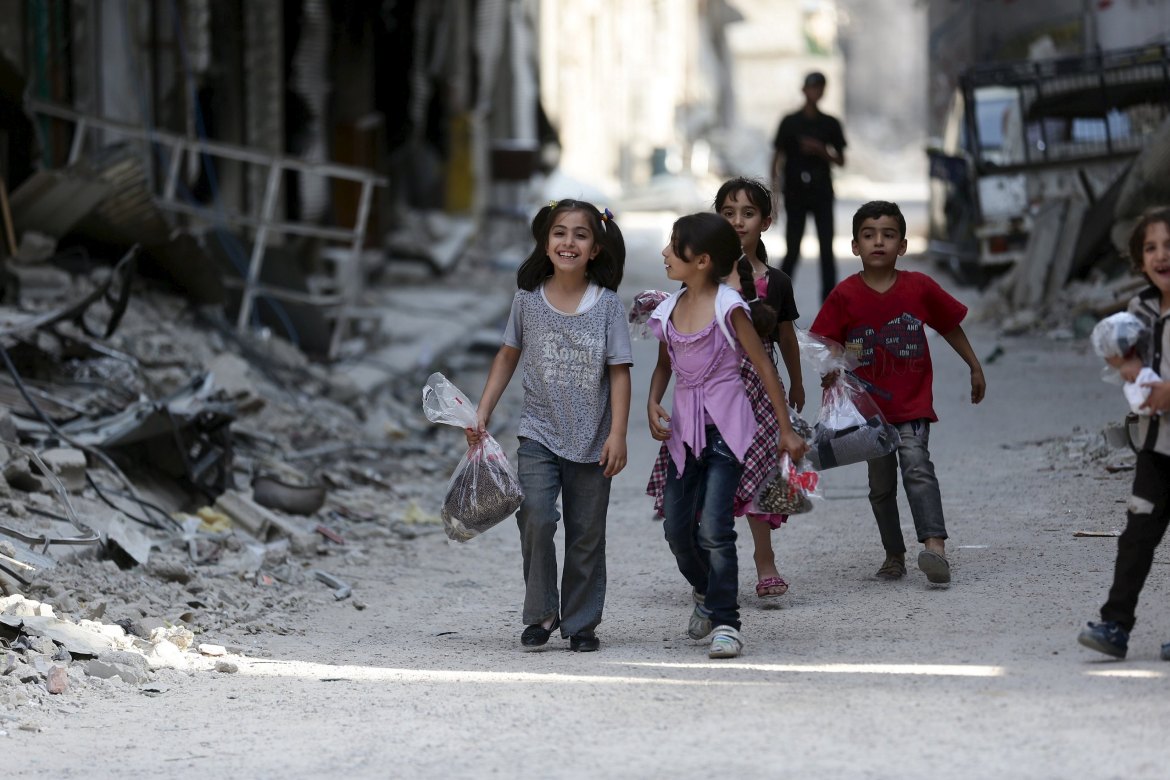 Children carry bags of new clothes ahead of the Eid al-Fitr holiday marking the end of Ramadan in Jobar, a suburb of Damascus, Syria July 15, 2015. Picture taken July 15, 2015. REUTERS/Bassam Khabieh
