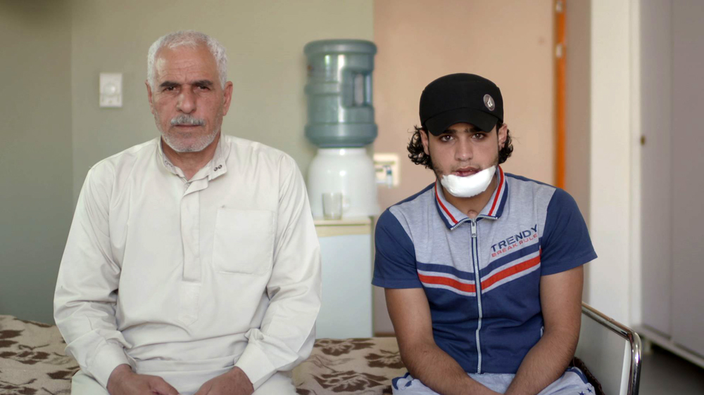 Mohamed Abdel-Muhsen, seated next to his father Hamad, had his chin blown off in Homs and is receiving ongoing reconstructive surgery [Anson Hartford/Al Jazeera]