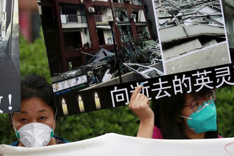 Residents evacuated from their homes after last week''s explosions at Binhai new district, hold placards bearing images of their damaged houses, at a rally demanding government compensation, in Tianjin