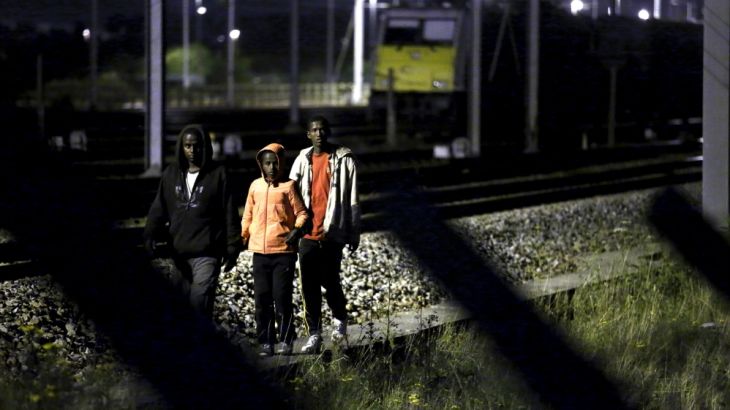 Migrants make their way along train tracks as they attempt to access the Channel Tunnel in Frethun, near Calais