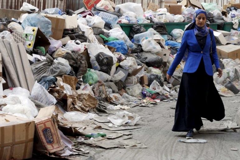 A woman walks past garbage piled up along a street in Beirut, Lebanon [REUTERS]