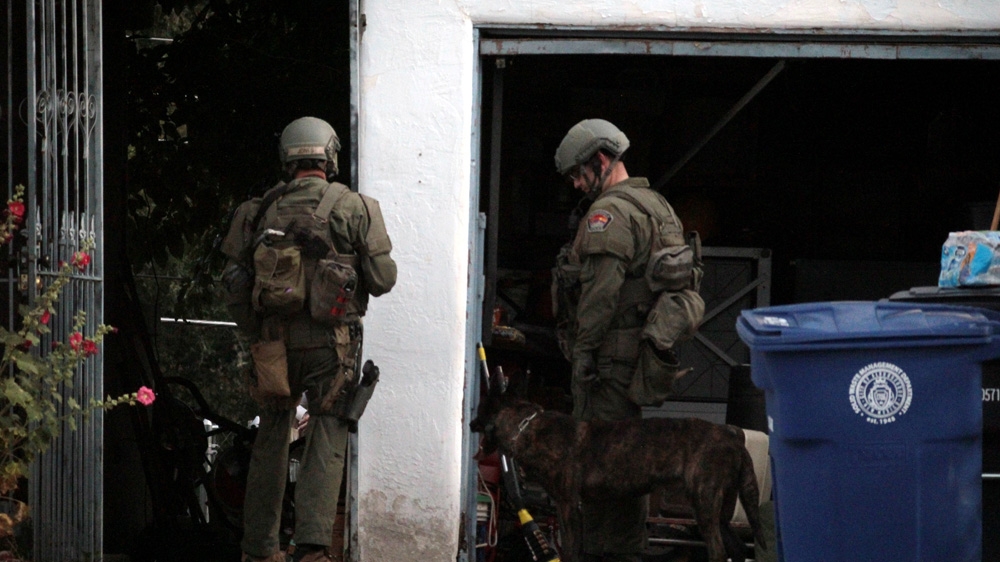 Members of Albuquerque's SWAT team surround a house during a standoff with a mentally ill man holding a saw and a shovel in June 2015 [Andy Beale/Al Jazeera] 