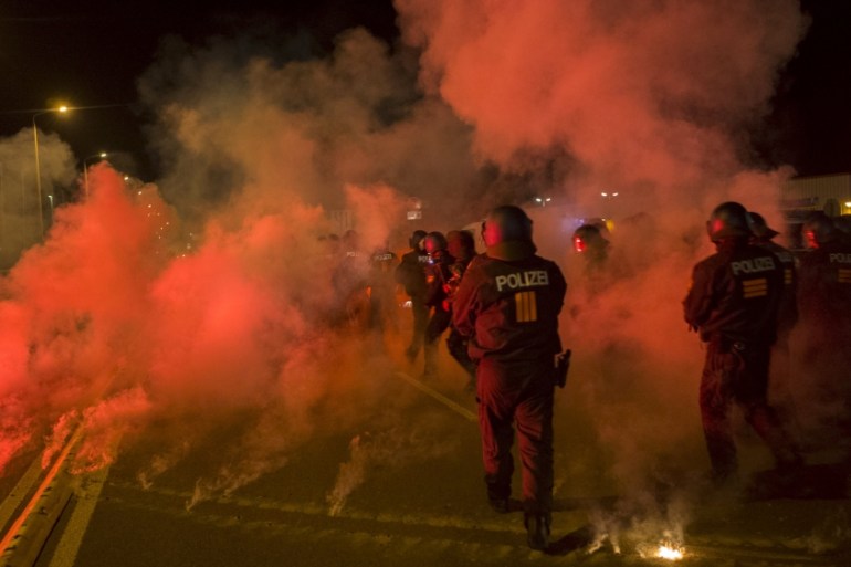 Policemen walk between flares thrown by right wing protesters who are against bringing asylum seekers to an accomodation facility in Heidenau
