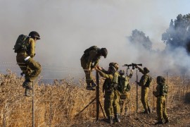 Israeli soldiers inspect fire caused by four missiles fired from the Syrian side of the Israeli-Syrian border