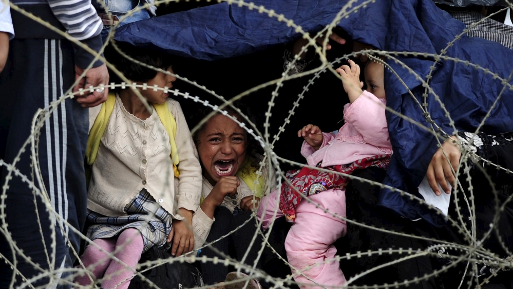 A girl cries as she tries to take shelter from the rain on Greece's border with Macedonia [Reuters]