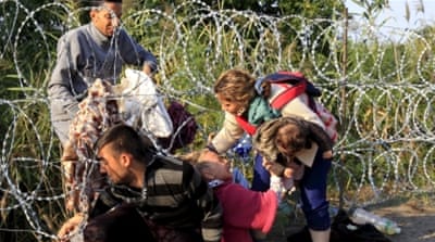 Syrian migrants cross under a fence as they enter Hungary at the border with Serbia [REUTERS]