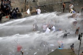 Lebanese protesters are sprayed with water during a protest against corruption and rubbish collection problems near the government palace in Beirut