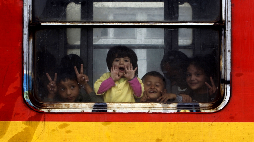 Children migrants look from a window on board a train departing towards Serbia, at the railway station in the southern Macedonia's town of Gevgelija [AP]