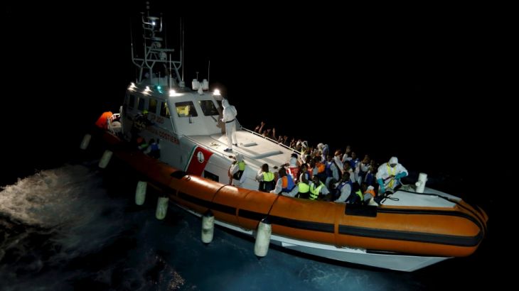 An Italian Coast Guard vessel pulls away from the Migrant Offshore Aid Station ship MV Phoenix after taking on board its rescued migrants between Libya and the Italian island of Lampedusa