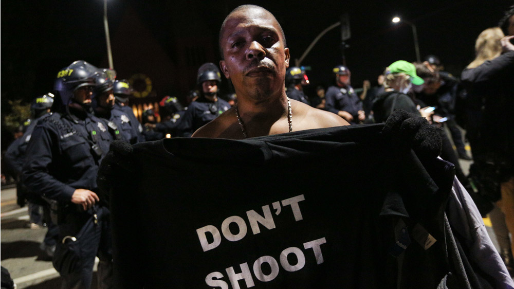 Mike Jones of Oakland holds a shirt reading 'Don't shoot' during a 'Millions March' demonstration protesting against the killing of unarmed black men by police on December 13, 2014 in Oakland, California. The march was one of many held nationwide [Elijah Nouvelage/Getty Images]