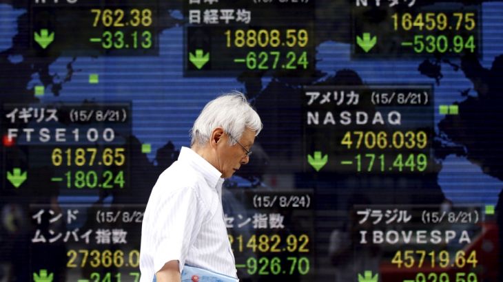 Man walks past an electronic board displaying Japan''s Nikkei average and various countries'' stock price index outside a brokerage in Tokyo