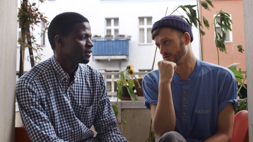 Jonas Kakoschke, right, and Bakary Conan chat as they pose for a photograph on the balcony of Kakoschke's flat in Berlin. Kakoschke gave shelter to Conan with his Refugees Welcome initiative. [AP]