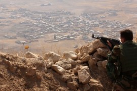 An Iraqi Kurdish Peshmerga fighter monitors his surrounding from the top of Mount Zardak, about 25 kilometres east of Mosul [AFP]