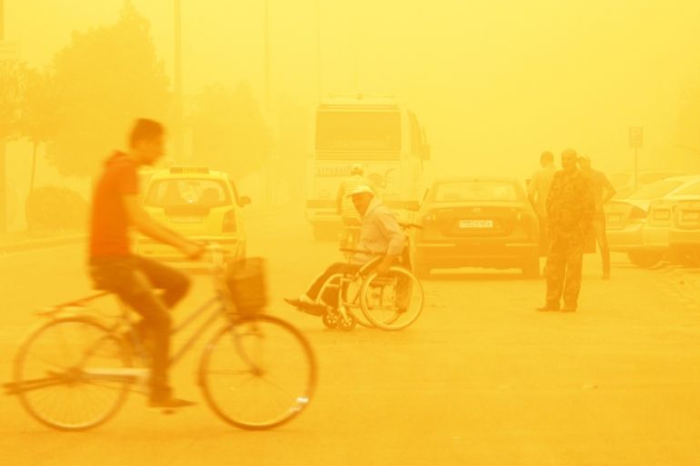 A man rides a bicycle through a sandstorm in Homs