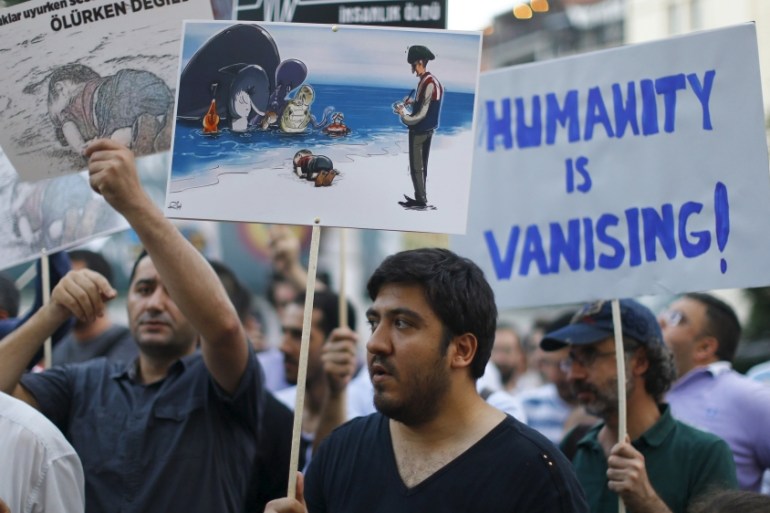People hold posters with drawings depicting a drowned Syrian toddler during a demonstration for refugee rights in Istanbul, Turkey [REUTERS]