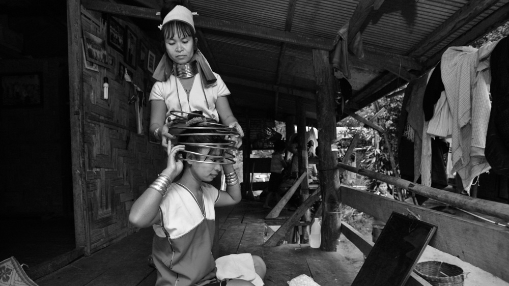 Twenty-three-year-old Zember has her neck rings removed by her sister. The coil is made of heavy brass weighing around 10lbs and takes specialist skill to put on and remove [Jack Picone] 