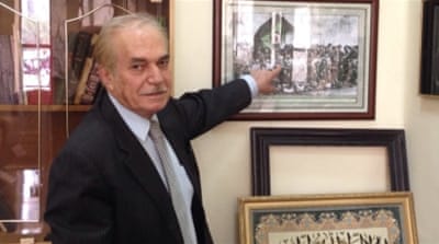 Sheikh Salar al-Hafeed, a lawyer and relative of Sheikh Mahmud, points to a portrait of Kurdish elders circa 1920s [Lara Fatah/Al Jazeera]