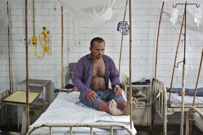 A patient awaits routine check-up as he sits under a mosquito net inside a dengue ward of a government hospital in New Delhi