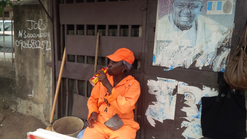 Kafayat takes a quick break from sweeping the streets [Abiodun Omotosho/Al Jazeera]