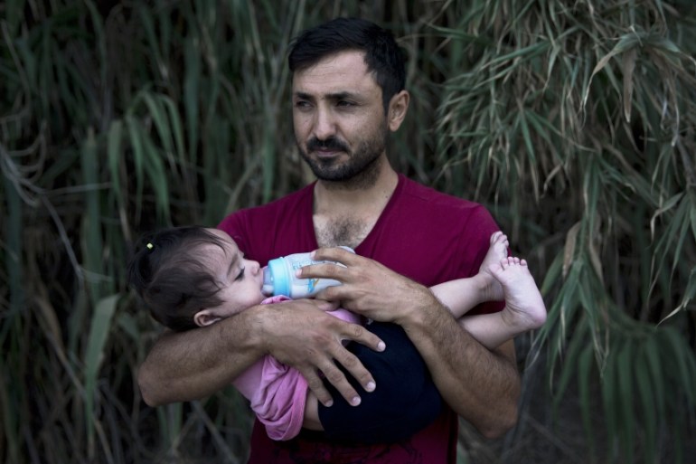 A Syrian refugee feeds his daughter after they arrived on a dinghy, from Turkey to Lesbos island, Greece [AP]