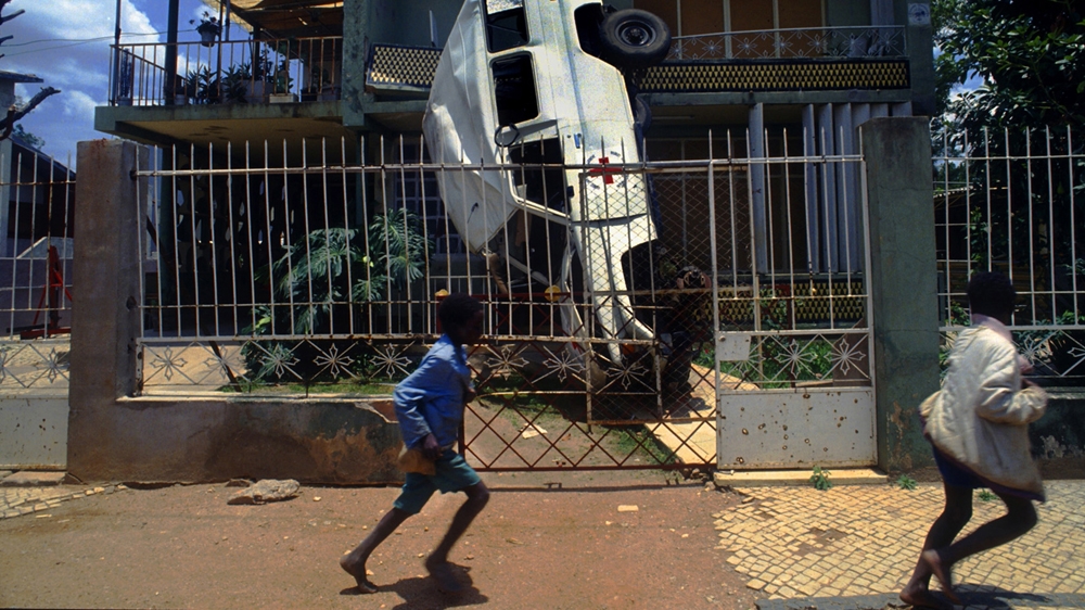 Angolan children run through the streets of Quito during a lull in the fighting. I was perplexed by how the vehicle had ended up on its side in such a tight space. 1993 [Jack Picone] 