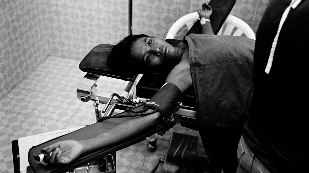 This 14-year-old landmine victim has his gangrene-infected leg amputated with a blunt saw and local anesthetic. He winced at times during the operation but did not scream. The smell of rotten flesh was putrefying. The operating theatre was about nine feet long and six feet wide. Flies buzzed around in the 120 degree heat but the staff worked in silence to complete the operation as quickly as possible. Thai-Myanmar border. 2006 [Jack Picone] 