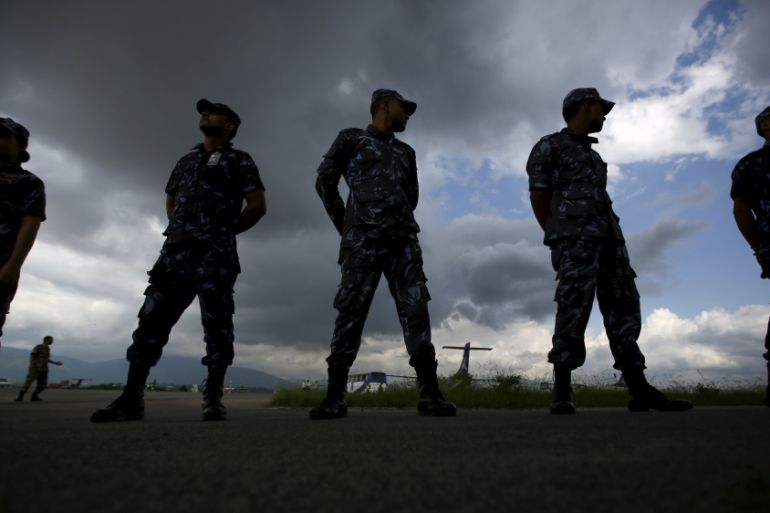 Nepali police are silhouetted as they wait for a helicopter carrying an injured policeman and the body of Senior Superintendent of Police (SSP) Laxman Neupane, in Kathmandu