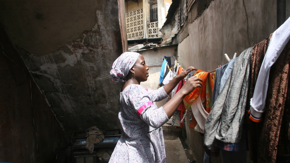 Kafayat does her family’s laundry. She says she has plans to leave her street sweeping job one day and to start her own business, but she just needs to save a little more money first [Abiodun Omotosho/Al Jazeera]