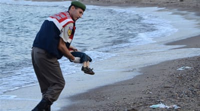 A Turkish police officer carries Aylan Kurdi's dead body off the shores in Bodrum, southern Turkey [AFP]