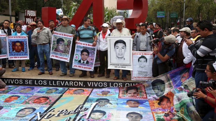 Relatives hold pictures of some of the 43 missing students of Ayotzinapa College Raul Isidro Burgos during a march to mark the first anniversary of their disappearance, in Mexico City