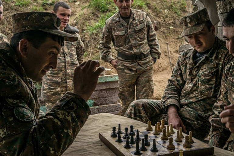 Members of the armed forces of Nagorno-Karabakh play checkers using a chess set at their post along the line of contact with Azerbaijani forces [Getty]