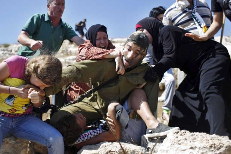 Palestinians scuffle with an Israeli soldier as they try to prevent him from detaining a boy during a protest against Jewish settlements in the West Bank village of Nabi Saleh [REUTERS]